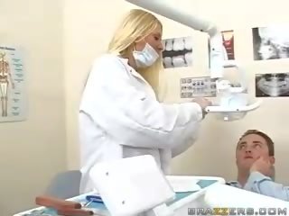 Vakker tenåring barmfager blond dentist viser henne pupper til en pasient